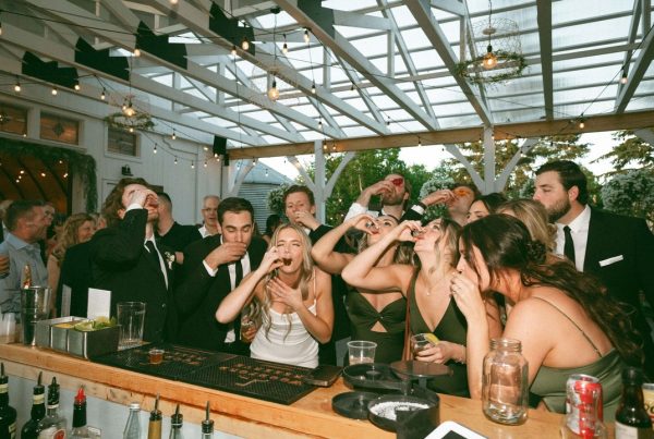 Group celebrating and taking shots at a lively event under a decorated pergola.