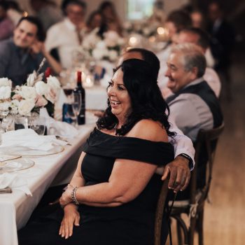 Guests enjoying a joyful wedding reception with elegant table settings and floral decor.